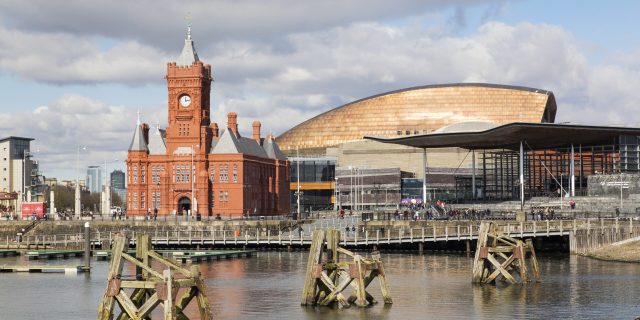 Cardiff, UK: March 10, 2016: Cardiff Bay is the area created by the Cardiff Barrage in South Cardiff, the capital of Wales. Tourists are enjoying the Millennium Centre, National Assembly and Pier Head Buildings.